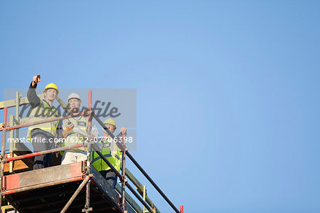 Workers standing on scaffolding on site