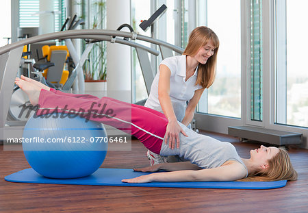 Trainer working with girl in gym