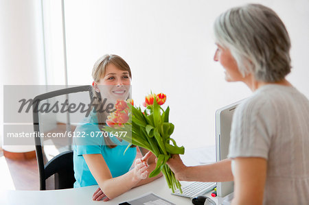 Woman handing receptionist flowers