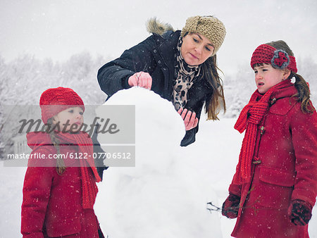 Mother and daughters building snowman