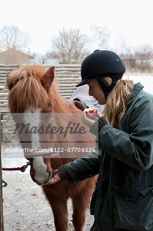 Woman feeding apple to horse outdoors