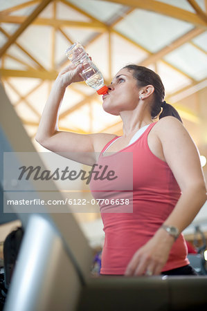 Woman drinking water bottle in gym