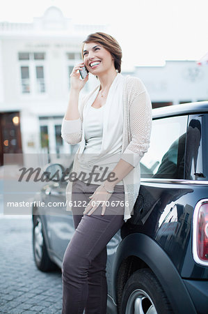 Woman talking on cell phone by car