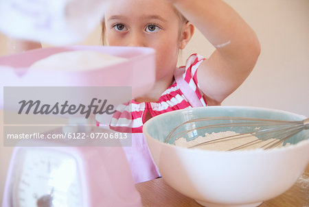 Girl weighing ingredients in kitchen