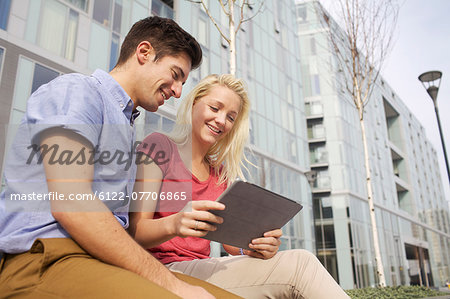 Couple using tablet computer on street