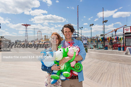 Portrait of couple with inflatable monkeys at amusement park