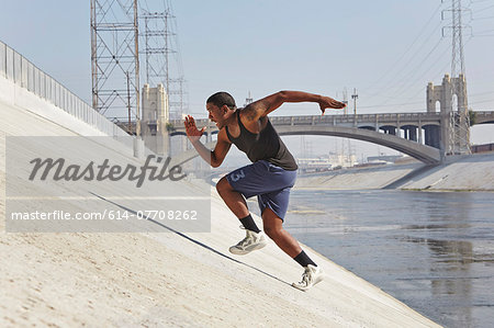 Young man speed running up riverbank Young man speed running up riverbank