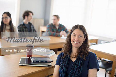 Teacher sitting at desk, portrait