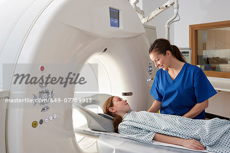 Radiographer reassuring girl going into CT scanner