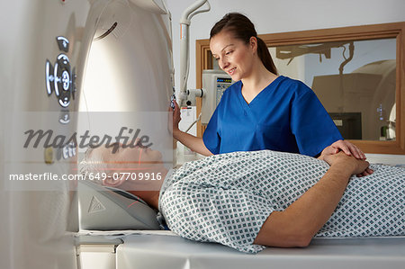 Radiographer reassuring man going into CT scanner Radiographer reassuring man going into CT scanner