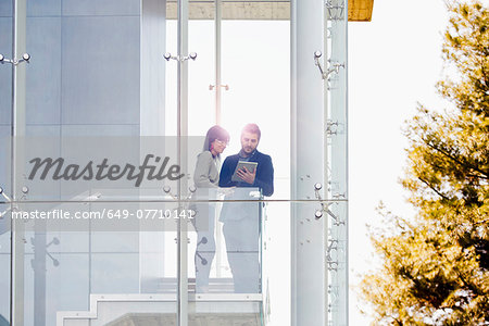 Businessman and woman using digital tablet at balcony