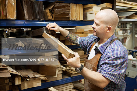 Guitar maker selecting wooden block in workshop