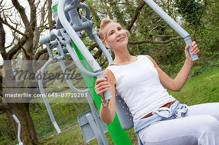 Mature woman using exercise machine in park