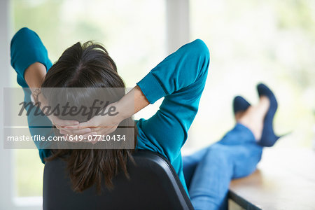 Mature woman with feet up on desk