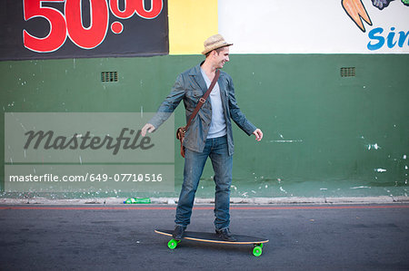Mid adult male skateboarding on city street