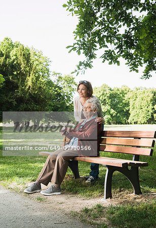 Senior woman sitting on park bench in park, with granddaughter