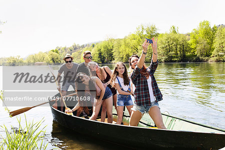 Group of friends in a row boat taking photo of themselves