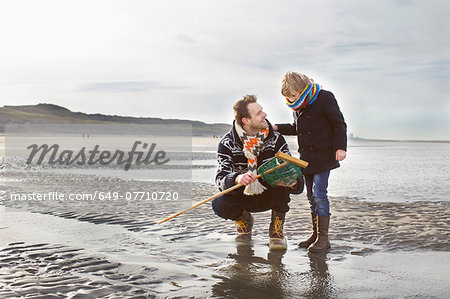 Mid adult man and son with fishing net on beach, Bloemendaal aan Zee, Netherlands