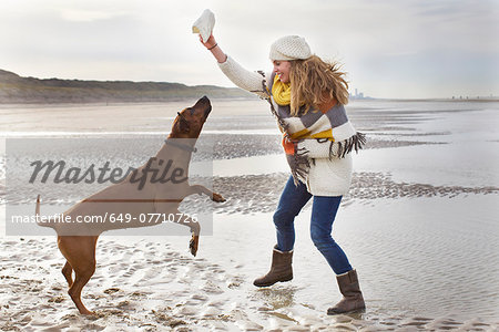 Mid adult woman teasing dog at beach, Bloemendaal aan Zee, Netherlands