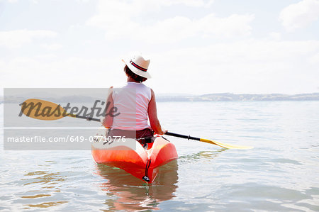 Rear view of senior woman sea kayaking