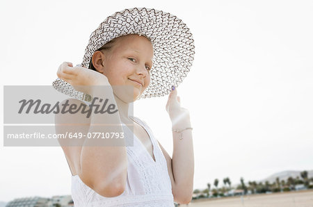 Portrait of girl holding her sunhat on beach