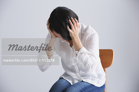 Desperate Japanese young woman in a white shirt sitting on a chair