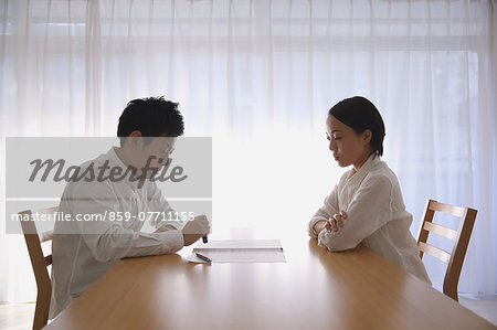 Young Japanese couple signing divorce papers