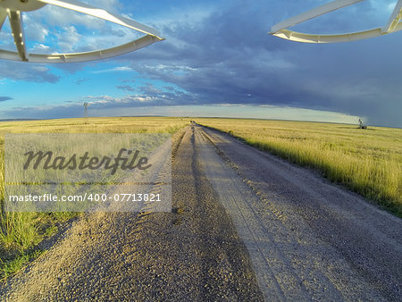 aerial view from a landing drone on a dirt road in Pawnee National Grassland with windmill and oil rig