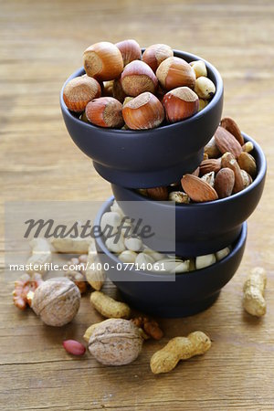 different kinds of nuts (almonds, walnuts, hazelnuts, peanuts) in a bowl on a wooden table