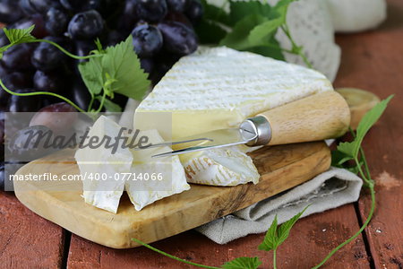 Soft brie cheese with sweet grapes on a wooden board