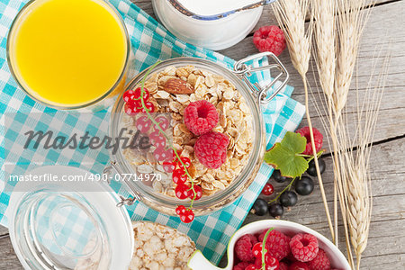 Healty breakfast with muesli, berries and orange juice. On wooden table