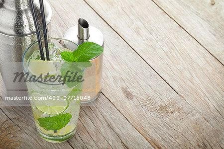 Fresh mojito cocktail and bar utensils. On wooden table with copy space
