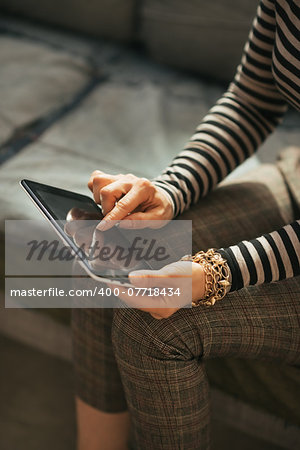 Closeup on young woman sitting on couch and using tablet pc