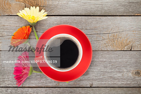 Cup of coffee and gerbera flowers on wooden table