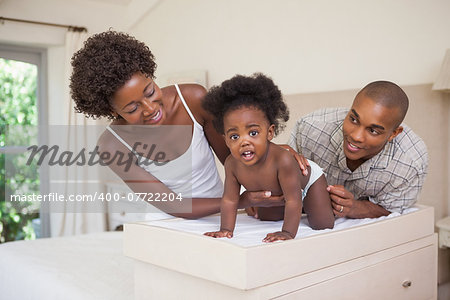 Happy parents with their baby girl on changing table at home in the bedroom