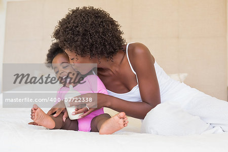 Happy parents with baby girl on their bed at home in the bedroom