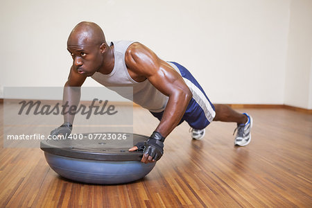 Full length of a muscular man doing push ups in gym