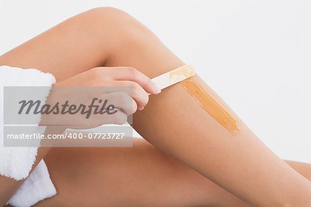 Close up side view of female applying hot wax on leg at spa center