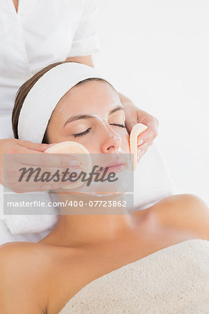 Hand cleaning woman's face with cotton swabs at spa center
