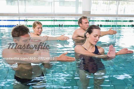 Happy fitness class doing aqua aerobics in swimming pool at the leisure centre
