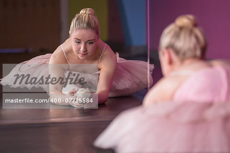 Graceful ballerina warming up in front of mirror in the ballet studio