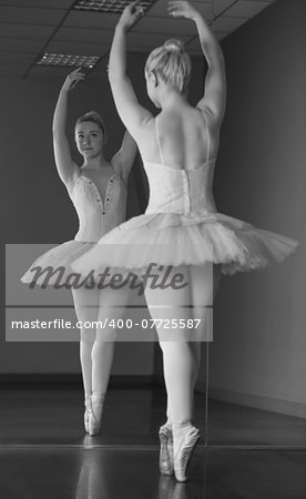 Graceful ballerina standing en pointe in front of mirror in the ballet studio