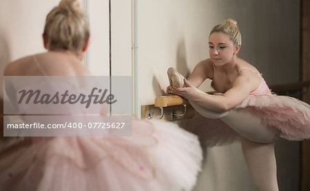 Beautiful ballerina warming up with the barre in the dance studio