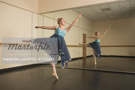 Beautiful ballerina dancing in front of mirror in the dance studio