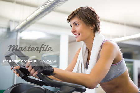 Fit smiling woman working out on the exercise bike at the gym