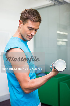 Fit man lifting heavy dumbbell at the gym