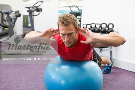 Fit man working his core on exercise ball at the gym