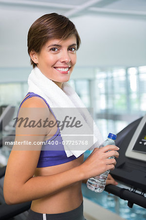 Fit brunette smiling at camera on the treadmill  at the gym