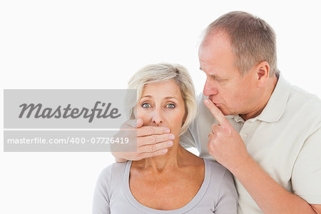 Man silencing his fearful partner on white background