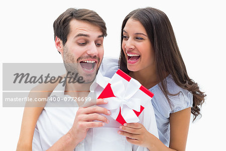 Pretty brunette surprising boyfriend with a gift on white background